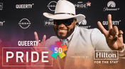 Image of model in cowboy hat posing in front of step and repeat.